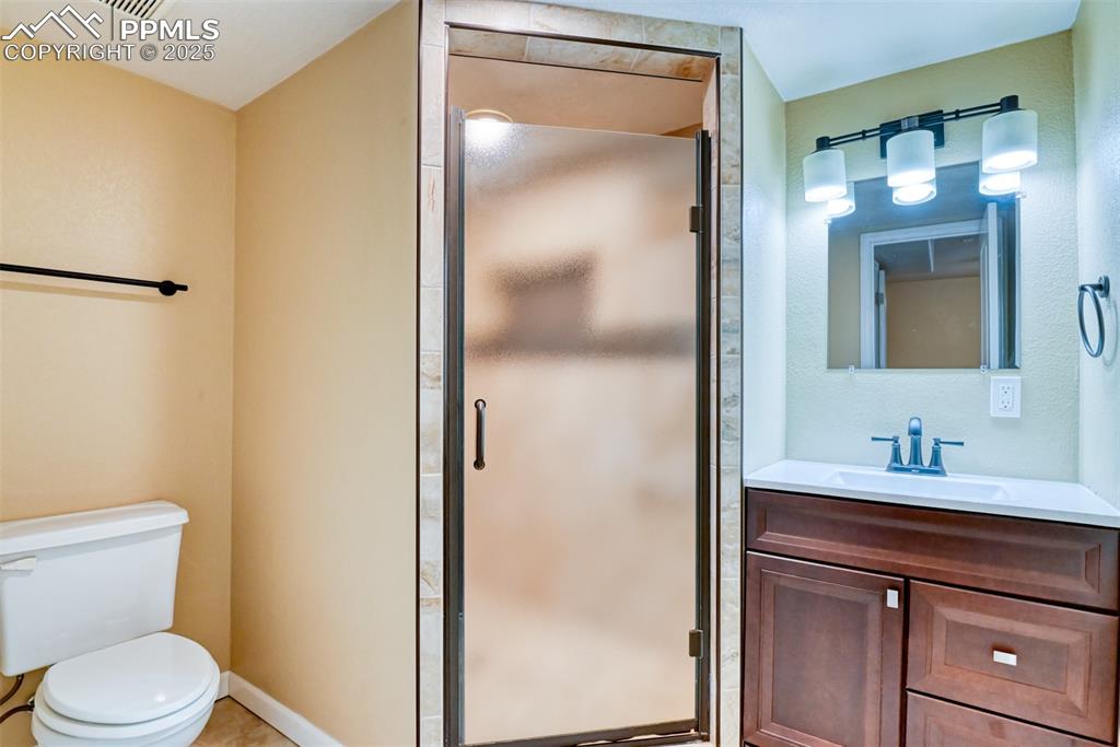 Image 32 of 36: Bathroom featuring toilet, a stall shower, and vanity