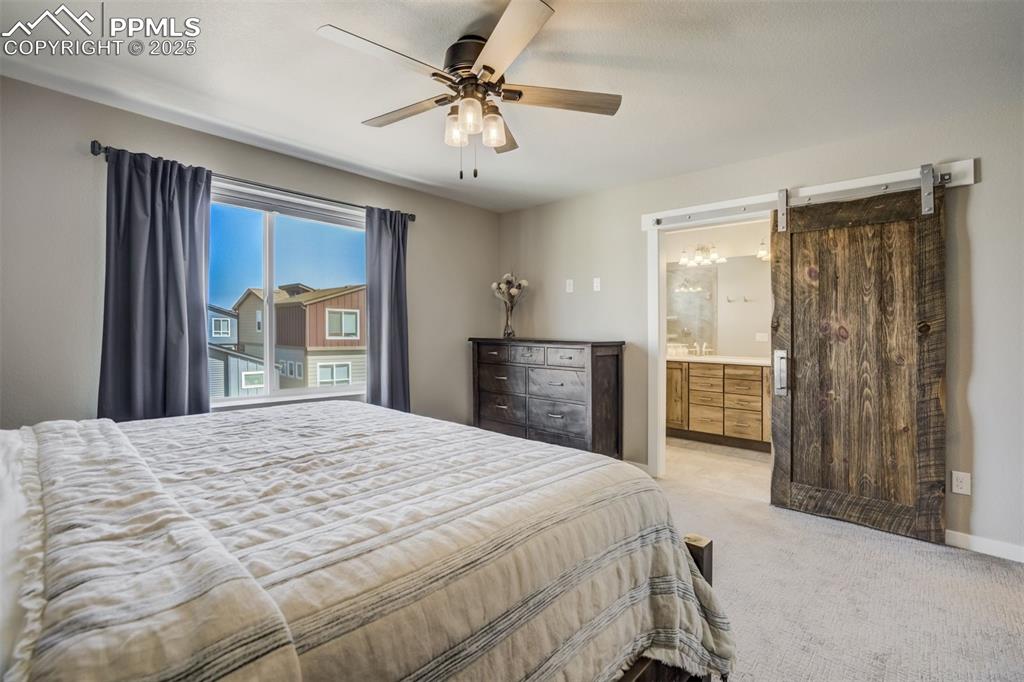 Image 22 of 45: Prim.bedroom, ceiling fan, barn door to on suite bath, walk in closet, blac