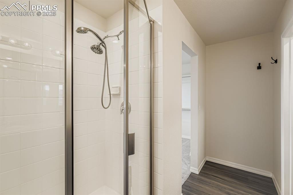 Image 13 of 26: Bathroom featuring a shower stall and dark wood-style flooring