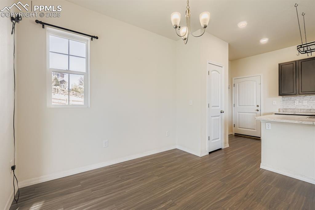 Image 19 of 26: Unfurnished dining area with dark wood-style floors and a chandelier