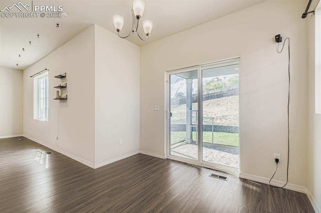 Image 25 of 26: Unfurnished dining area featuring dark wood-type flooring and a chandelier