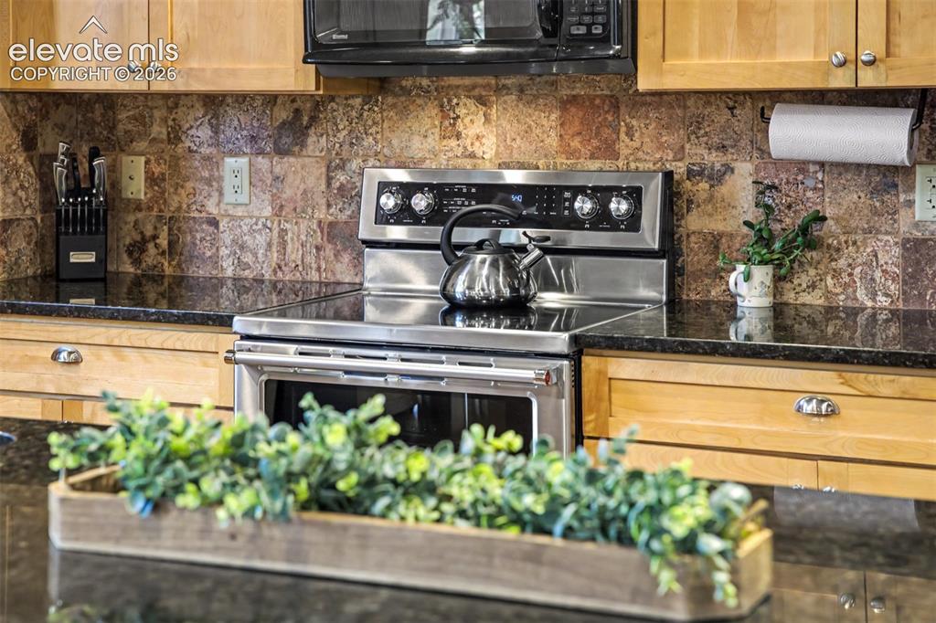 Image 13 of 50: A tiled backsplash, custom birch cabinetry and generous prep space make the