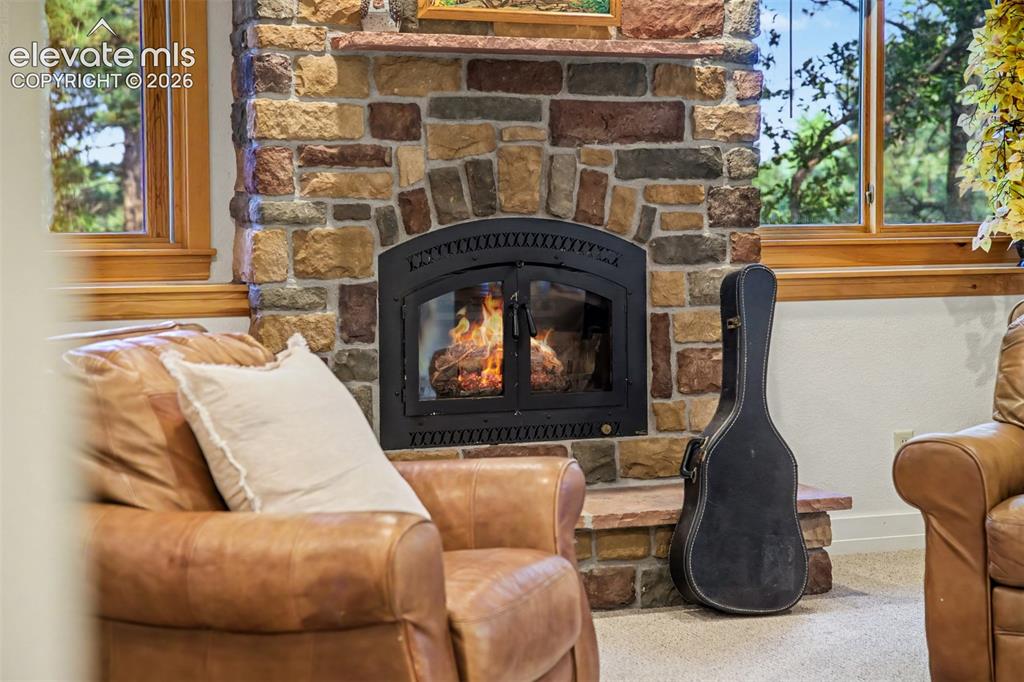 Image 35 of 50: The wood-burning fireplace creates a warm focal point in the basement famil