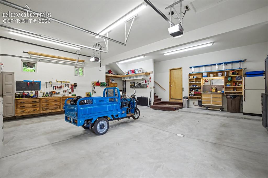 Image 40 of 50: The oversized garage offers abundant storage and workshop space, with a pri
