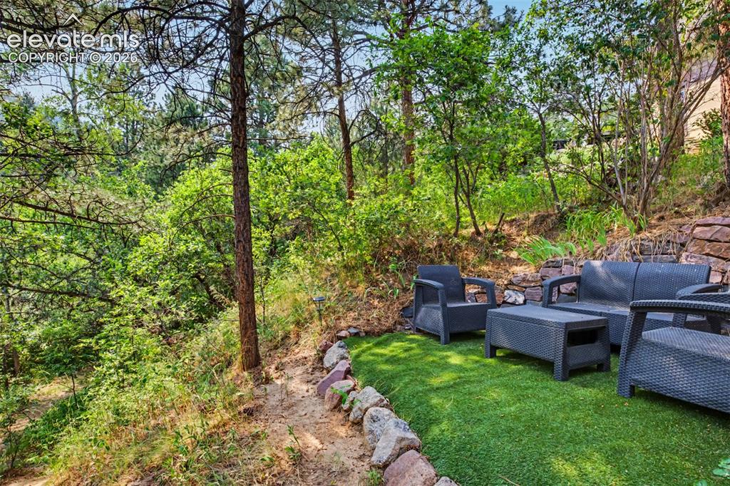 Image 41 of 50: A secluded outdoor sitting area beneath the trees offers a peaceful place t
