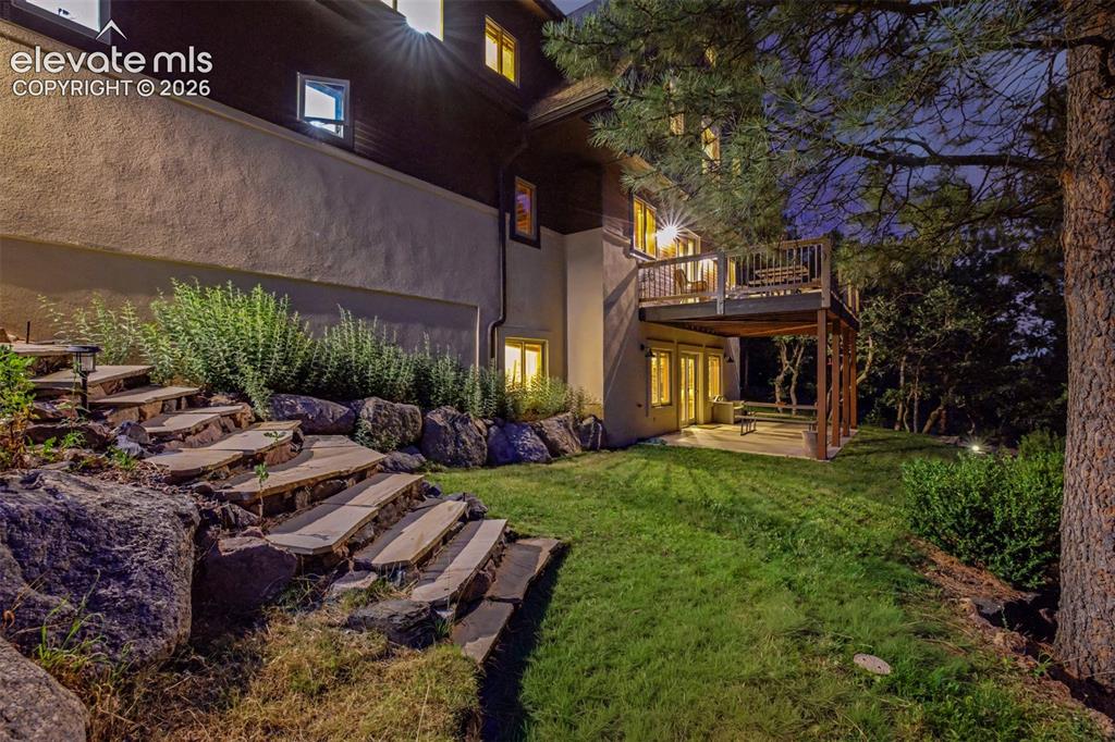 Image 8 of 50: Natural stone steps lead through the backyard to the covered walk-out patio