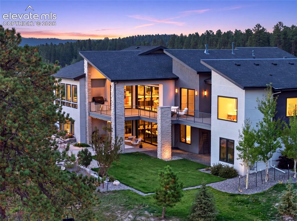 Caption: Multi-level contemporary exterior with stone and stucco finishes, multiple balconies, and a manicure