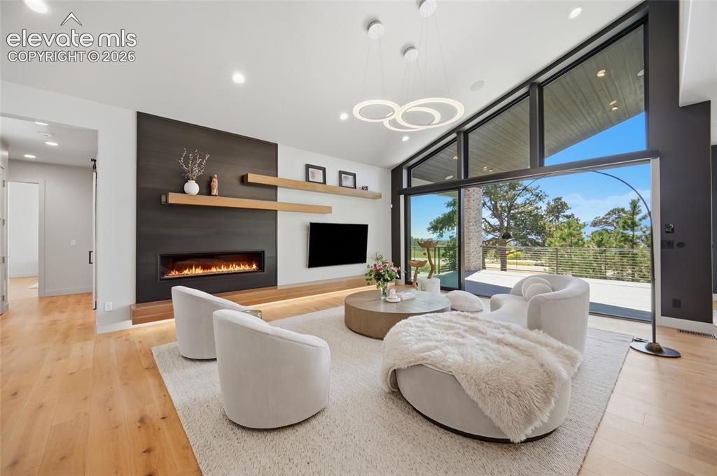 Image 14 of 50: Hardwood flooring, linear fireplace, built-in shelving, vaulted ceilings, a