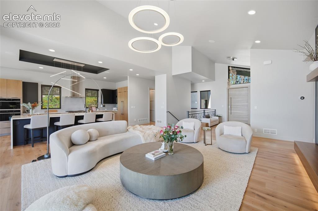 Image 16 of 50: Open-concept living space featuring wood-finish flooring, a contemporary ki