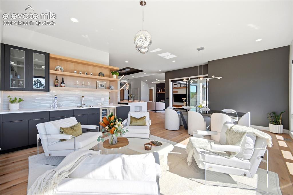 Image 24 of 50: Integrated living area featuring wood-finish flooring, a built-in wet bar w