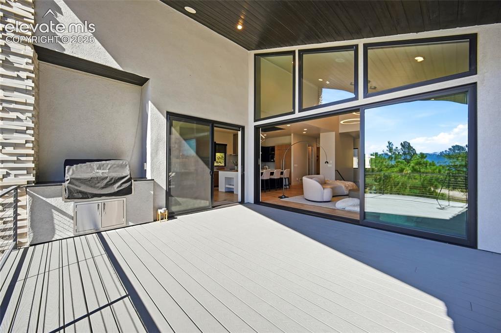 Image 26 of 50: Expansive outdoor deck with gray wood-finish flooring, featuring a built-in