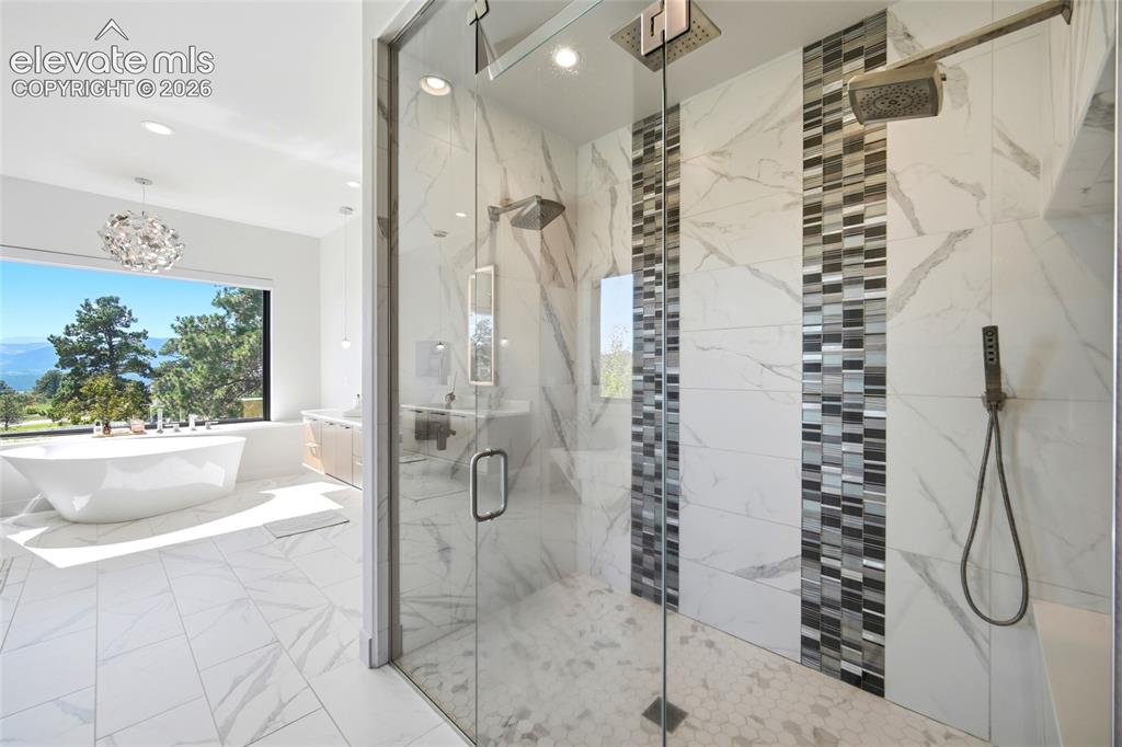Image 32 of 50: Freestanding bathtub with a large picture window, glass-enclosed shower wit