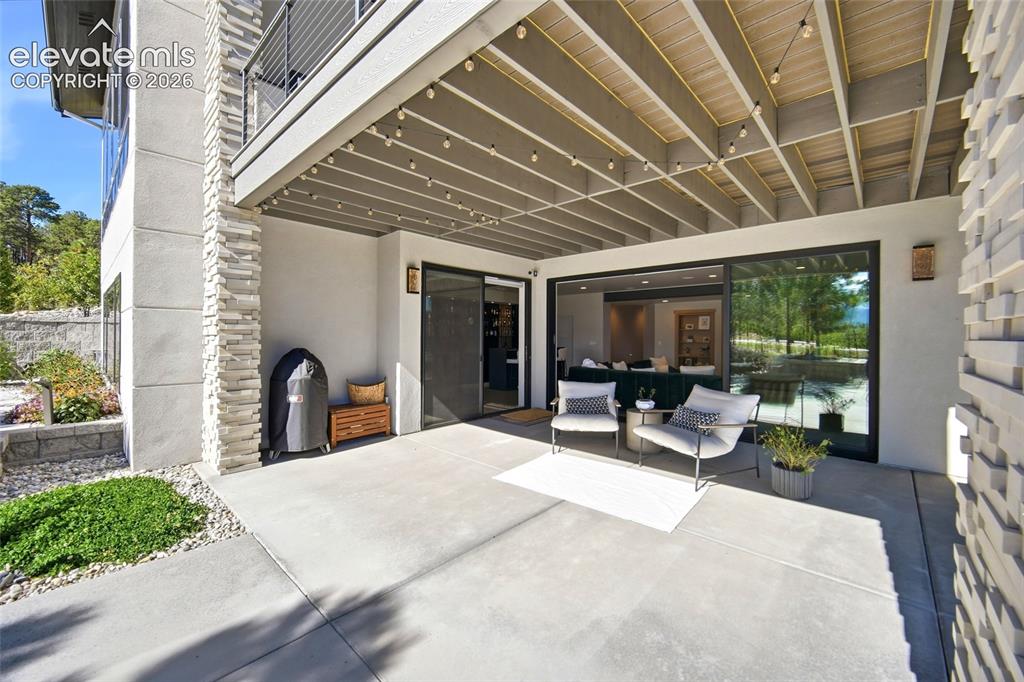 Image 37 of 50: Expansive covered patio with concrete flooring, sliding glass doors, and a