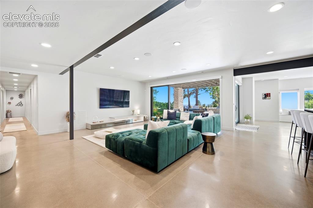 Image 39 of 50: Polished concrete flooring, recessed lighting, and a sliding glass door ope