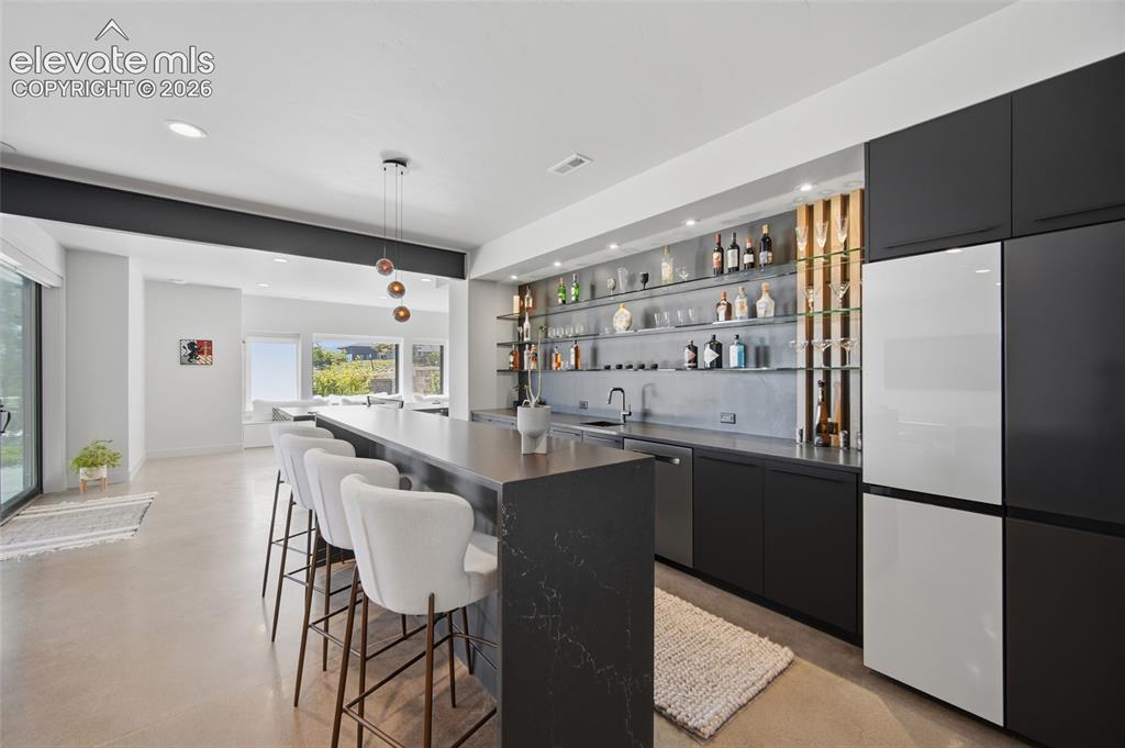 Image 40 of 50: Integrated wet bar with extensive open shelving, a built-in refrigerator, a