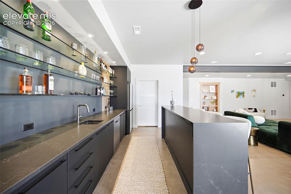Image 41 of 50: Wet bar featuring a stainless steel sink, sleek dark cabinetry, and integra