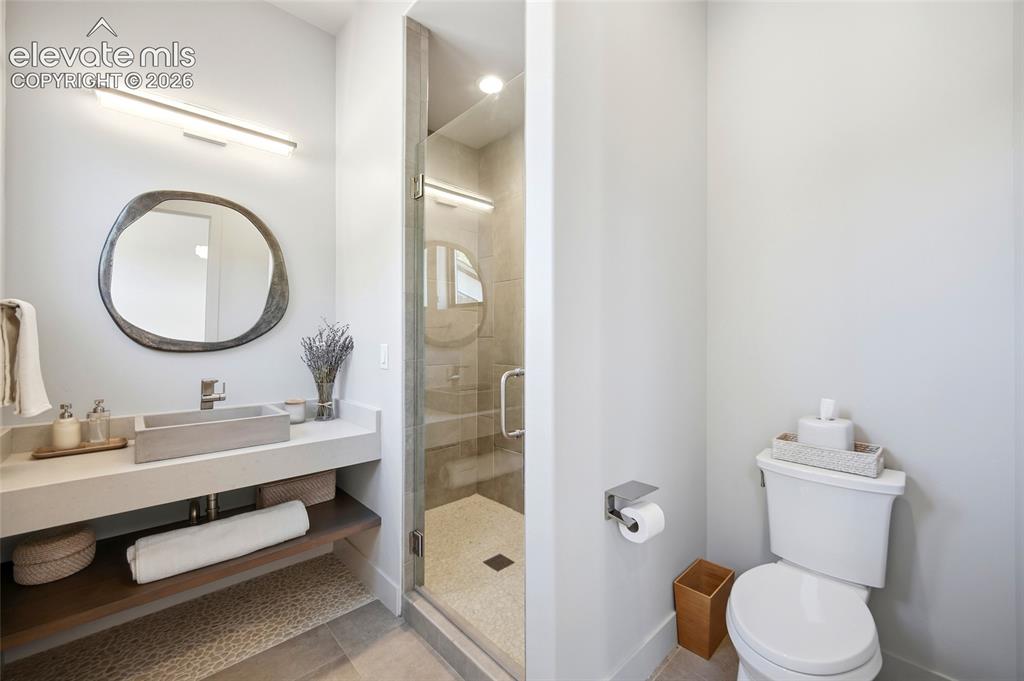 Image 44 of 50: Floating vanity with a rectangular basin sink, under-cabinet shelving, and