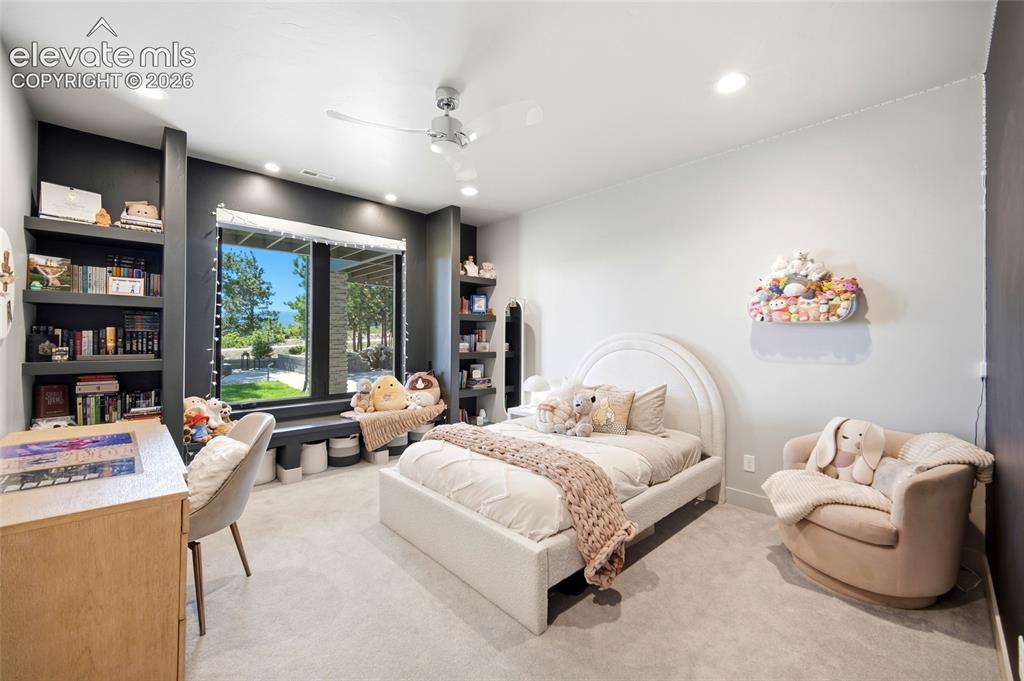 Image 45 of 50: Built-in shelving, expansive window, recessed lighting, ceiling fan, and li