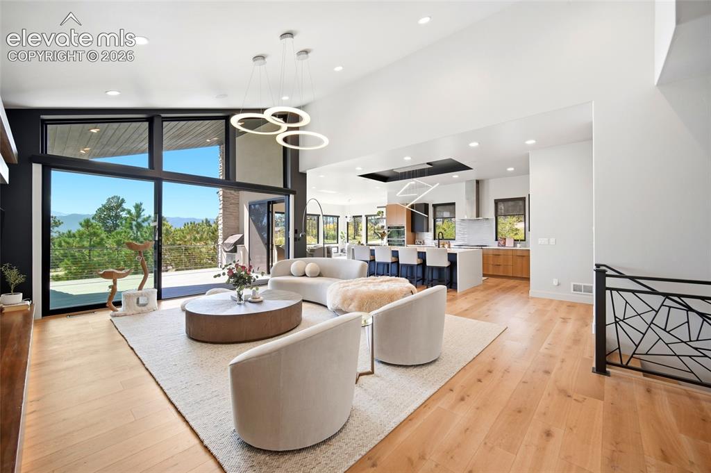 Image 6 of 50: Expansive floor-to-ceiling glass doors, wood-finish flooring, recessed ligh