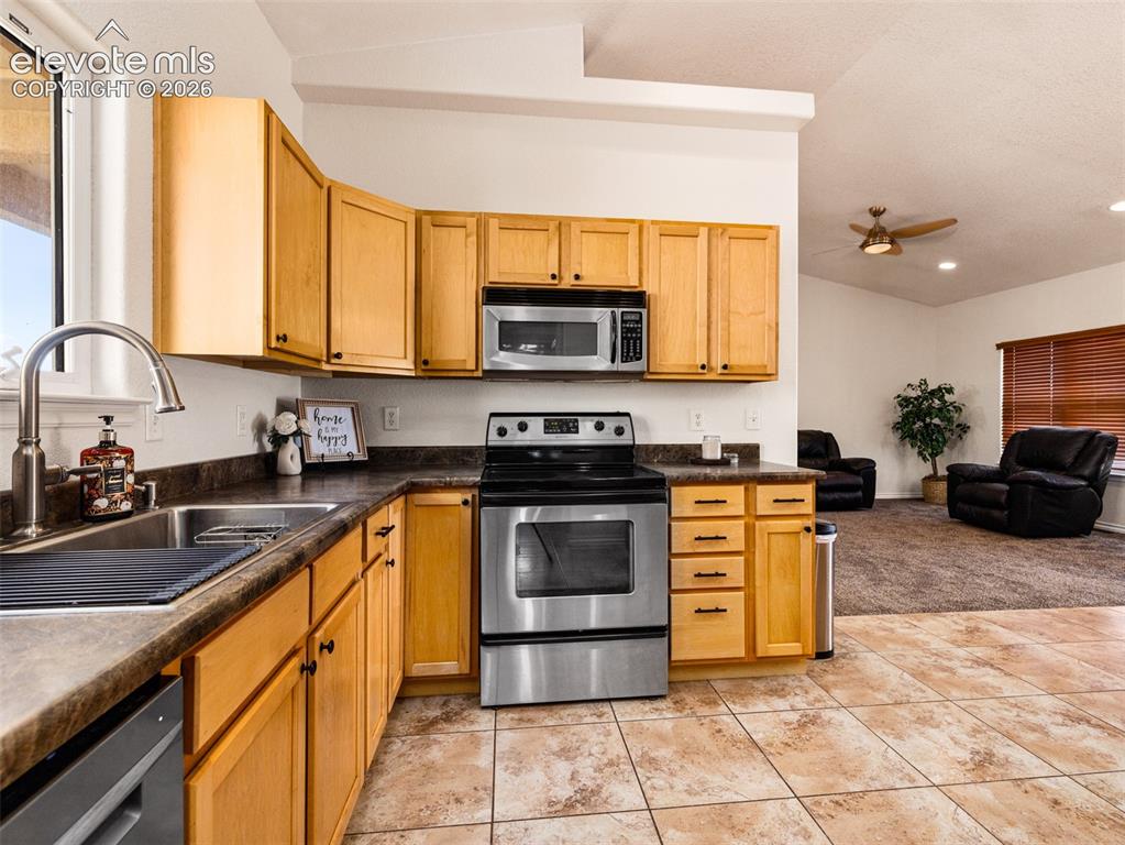 Image 10 of 49: Kitchen featuring wood-finish cabinetry, stainless steel appliances, and a