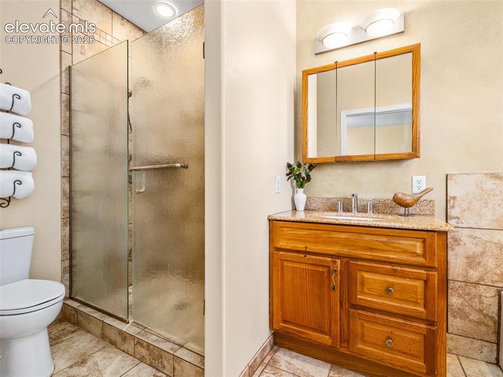 Image 13 of 49: Walk-in shower with frosted glass enclosure, tile surround, and recessed li