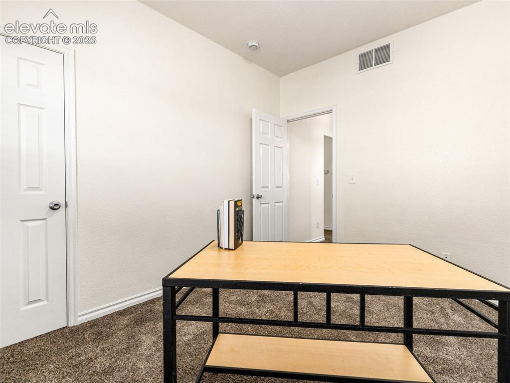 Image 16 of 49: Carpeted room with white walls and a white paneled door
