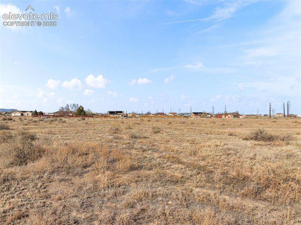 Image 28 of 49: Expansive undeveloped land with distant residential structures and utility 
