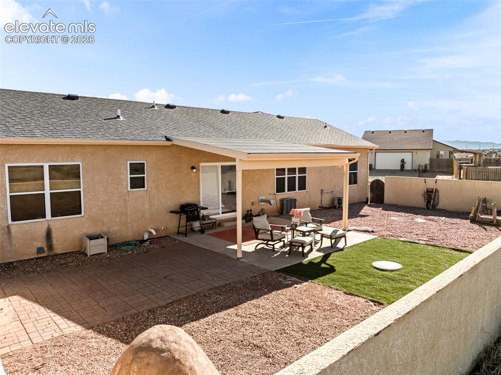 Image 30 of 49: Expansive backyard featuring a covered patio, artificial turf area, and a p
