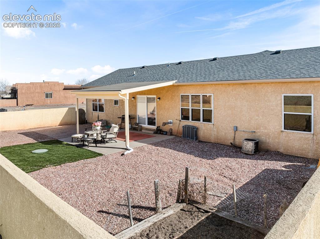 Image 31 of 49: Expansive backyard featuring a covered patio, xeriscape landscaping, a smal