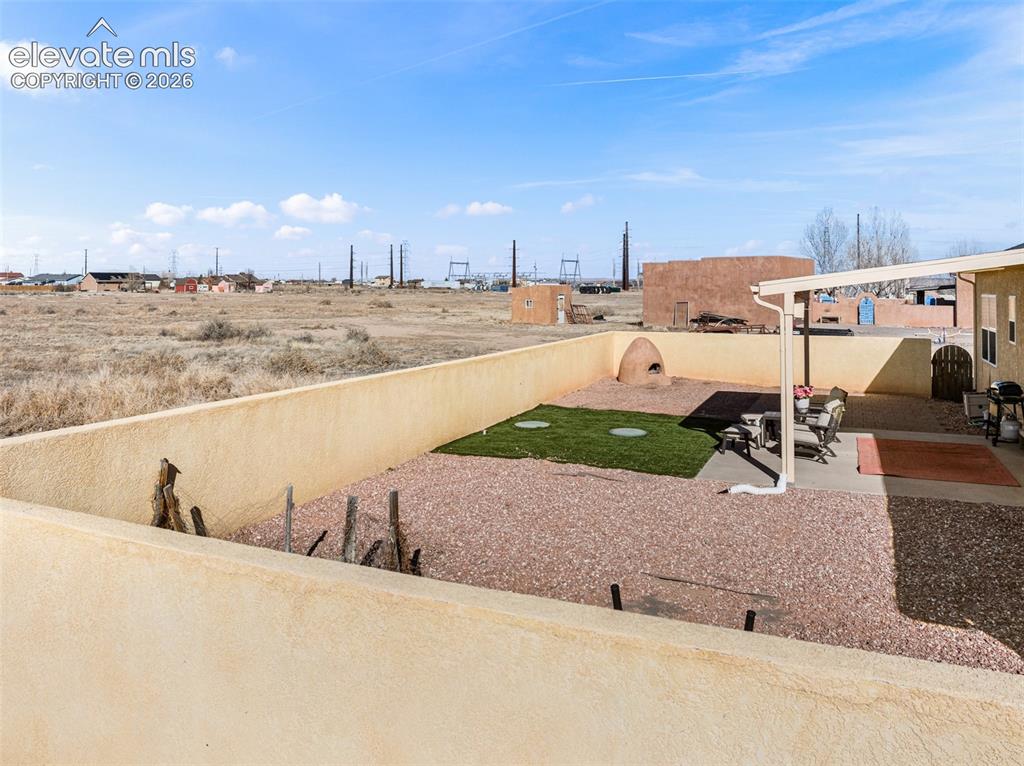 Image 32 of 49: Walled backyard featuring a covered patio, gravel landscaping, and a built-