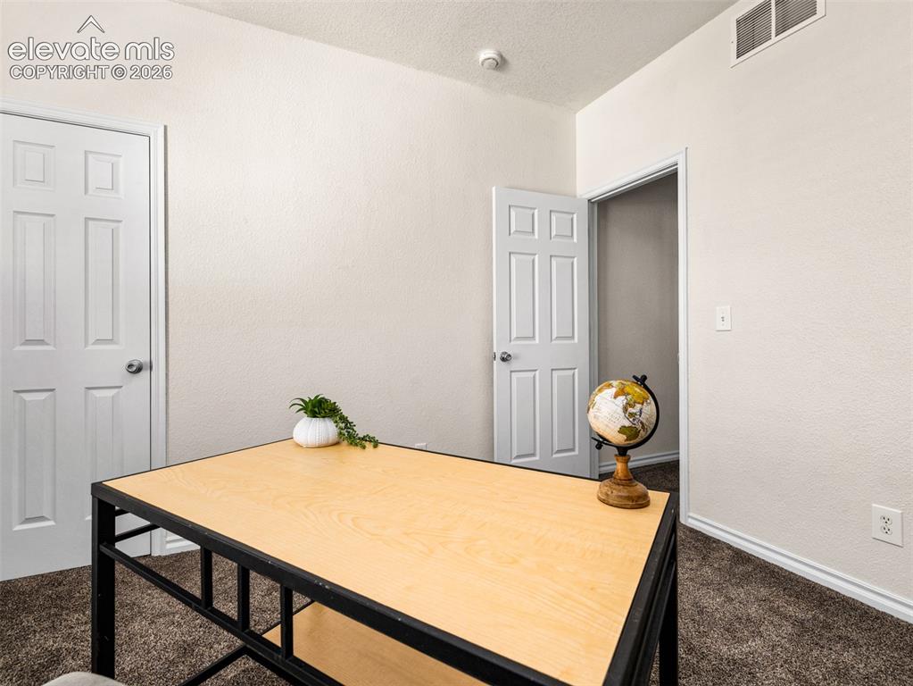 Image 37 of 49: Textured walls in a neutral tone, white trim, and brown carpet flooring