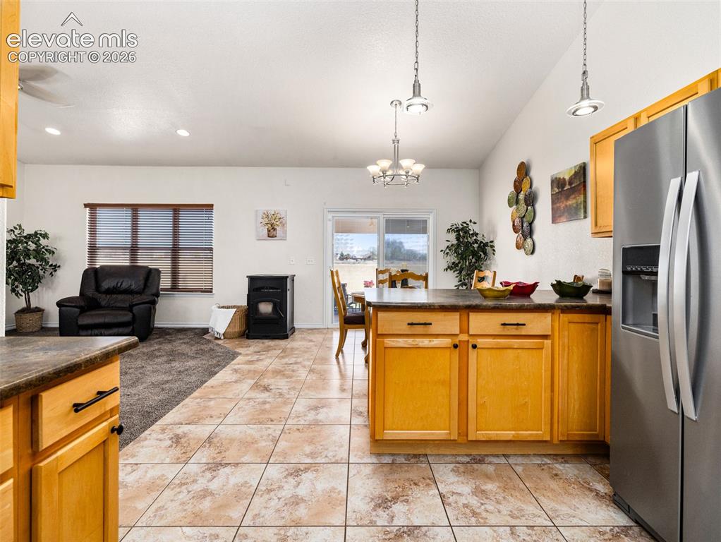 Image 45 of 49: Kitchen island with wood cabinetry and dark countertops
