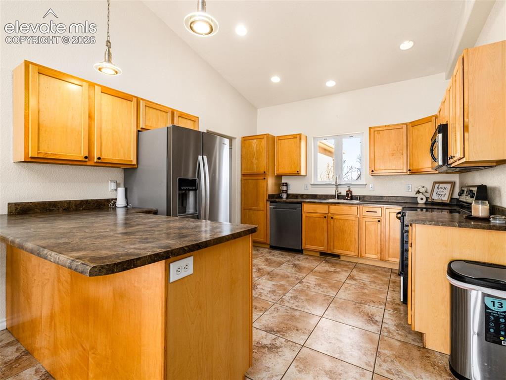 Image 8 of 49: Vaulted ceiling with recessed lighting, stainless steel appliances, wood-fi