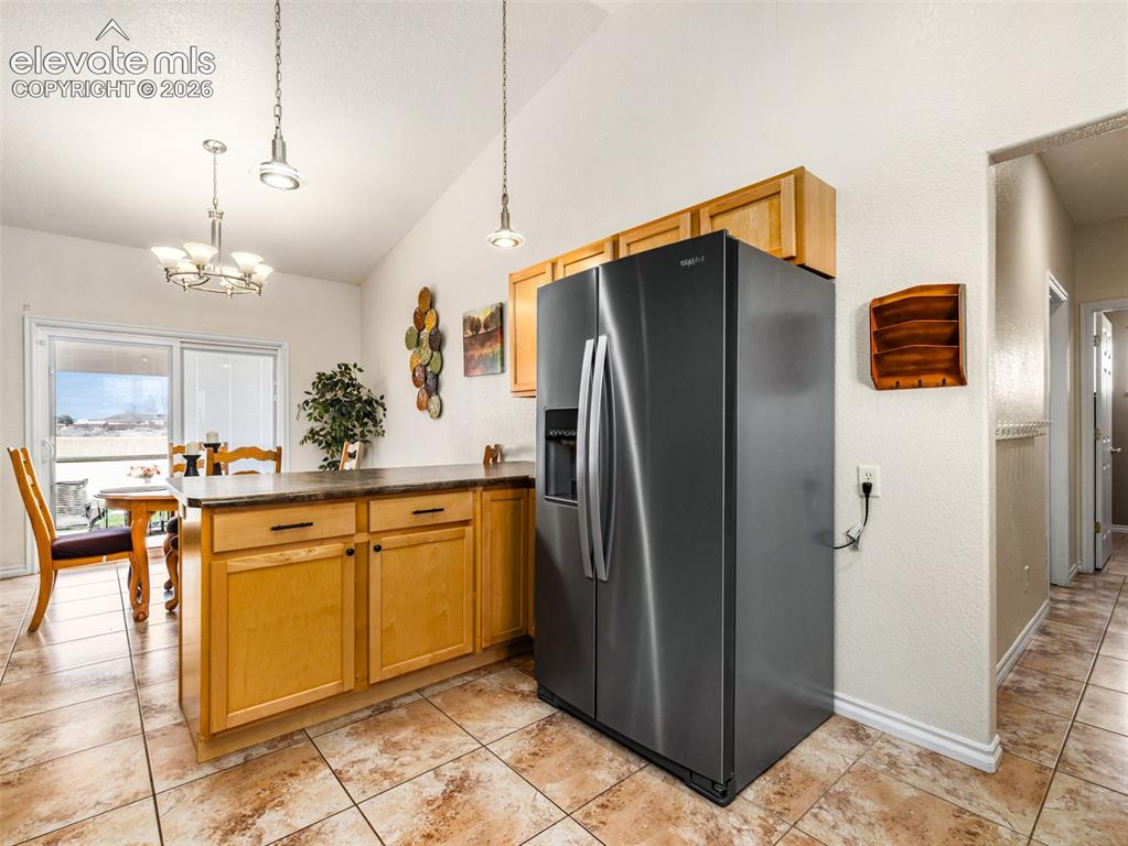 Image 9 of 49: Vaulted ceiling, recessed lighting, wood cabinetry, stainless steel refrige
