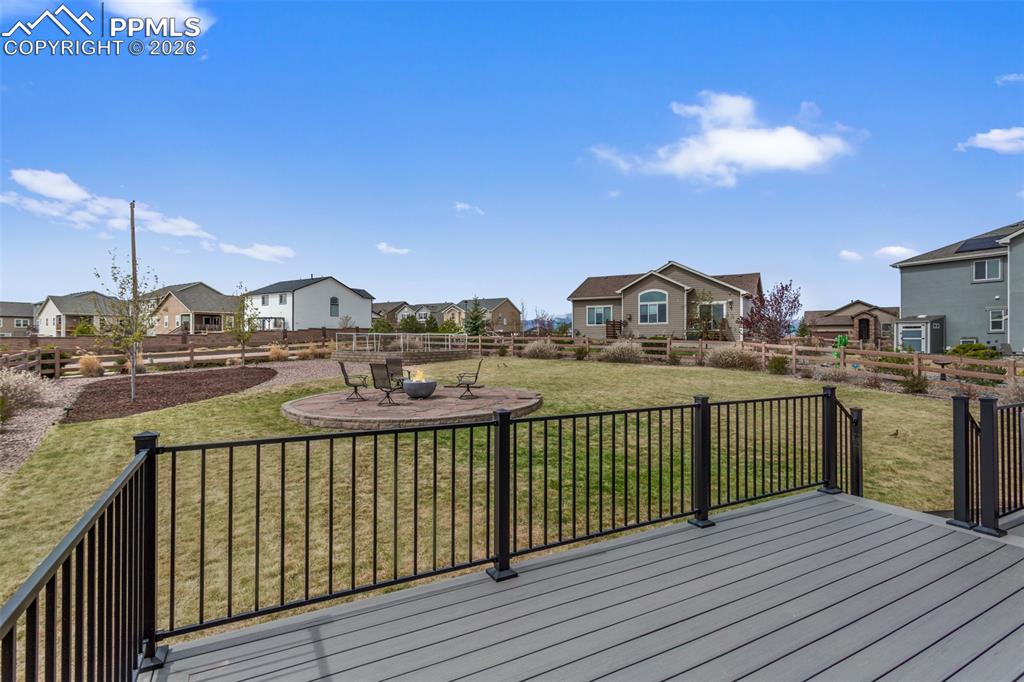 Image 18 of 21: Composite decking with black metal railing, featuring an expansive lawn, a 