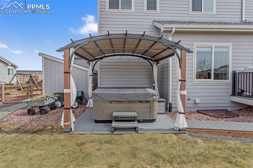 Image 20 of 21: Covered hot tub area on a composite deck, featuring a metal gazebo frame wi