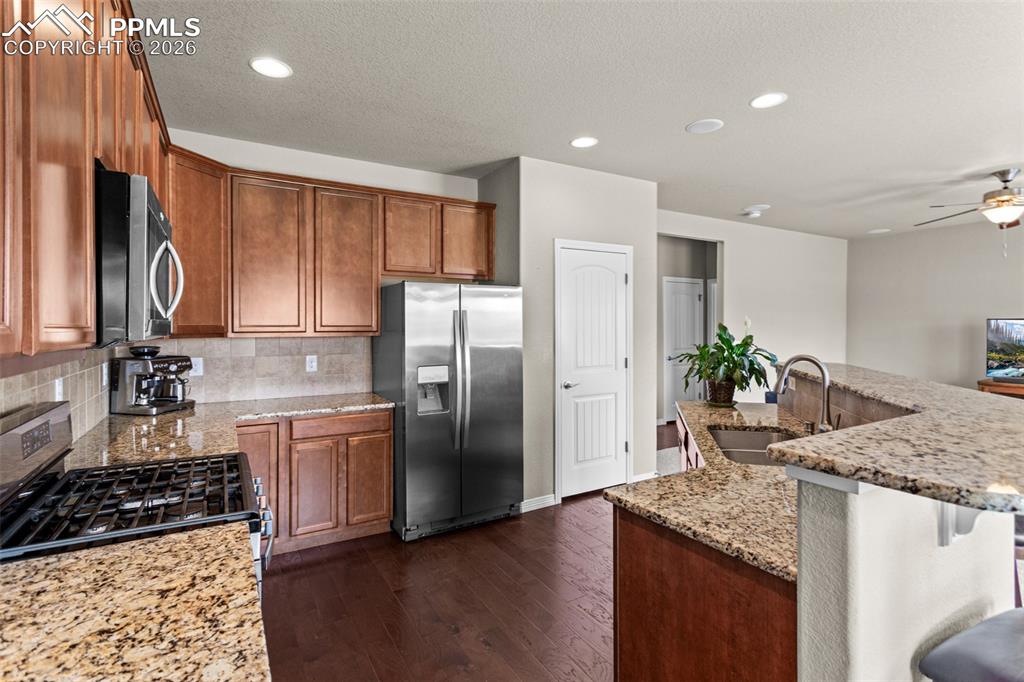 Image 5 of 21: Kitchen featuring wood-finish cabinetry, stainless steel appliances, stone 