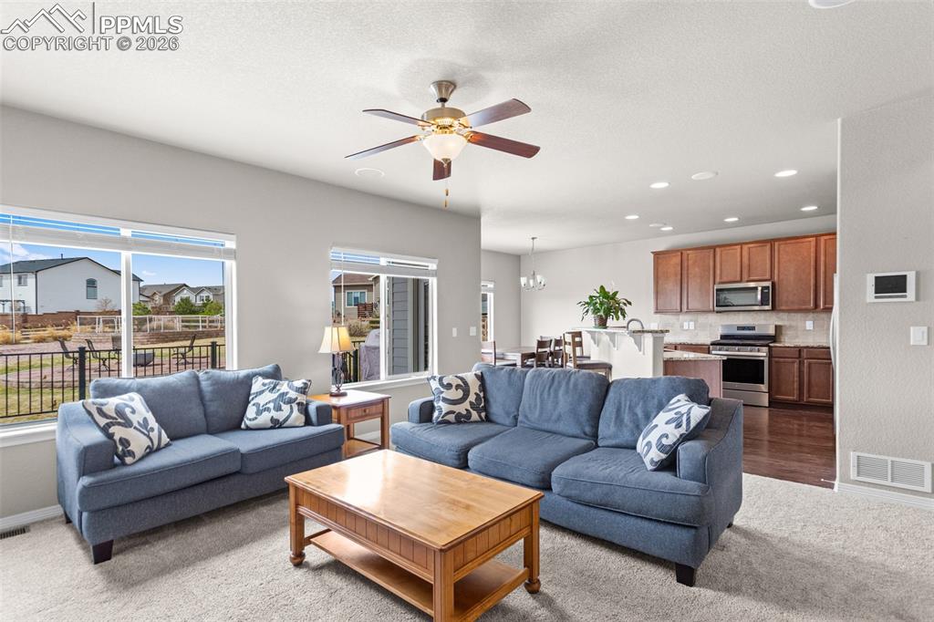 Image 8 of 21: Open-concept living space featuring carpeted flooring, large windows, and a