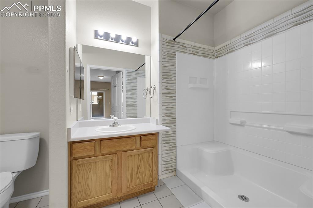Image 13 of 18: Full bath with tile patterned flooring, a shower, and vanity