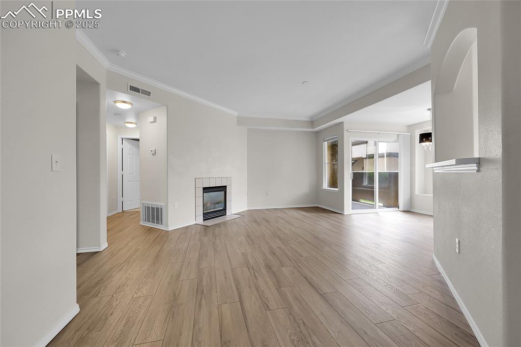 Image 2 of 18: Unfurnished living room with crown molding, light wood-style floors, and a 