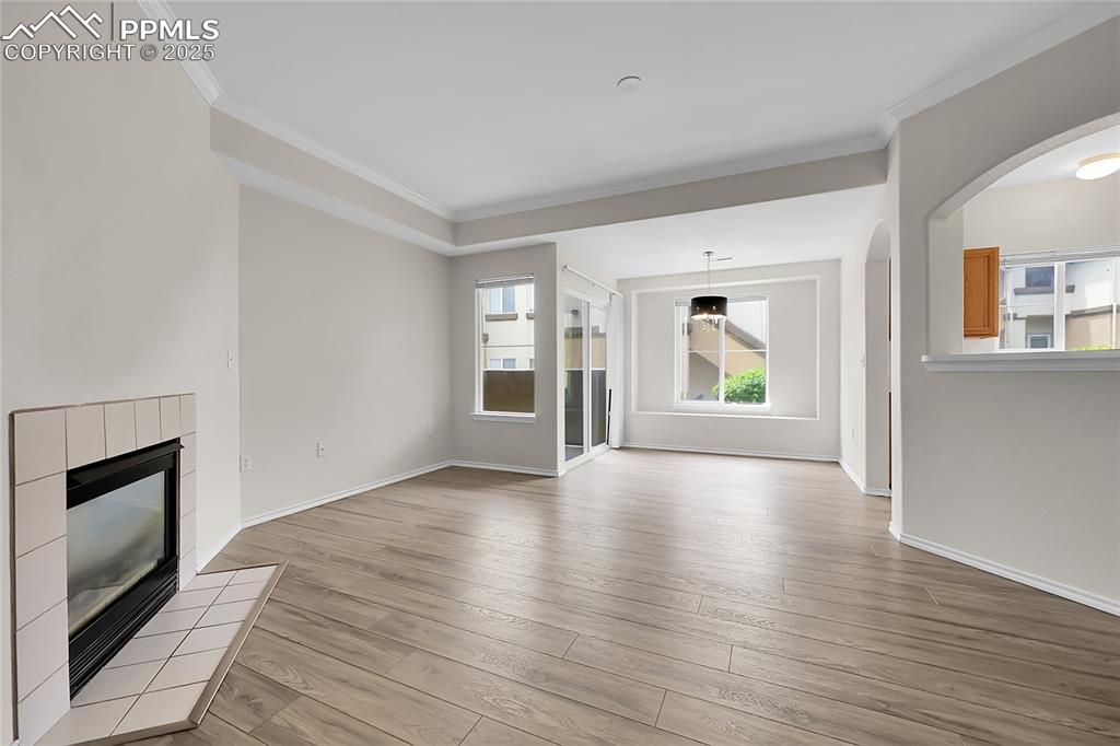 Image 3 of 18: Unfurnished living room with crown molding, light wood-style floors, a fire