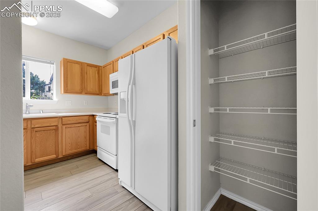 Image 7 of 18: Kitchen with white appliances, light wood-style floors, and light counterto