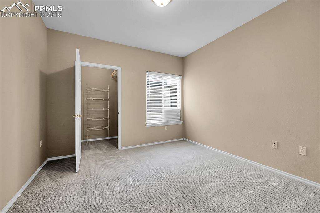 Image 9 of 18: Unfurnished bedroom featuring a walk in closet, light carpet, and a closet