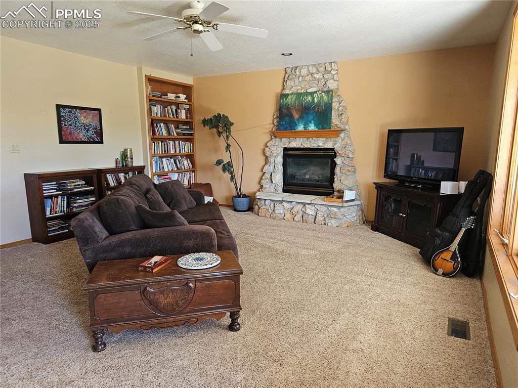 Image 12 of 44: Living area with carpet flooring, a textured ceiling, a fireplace, and a ce