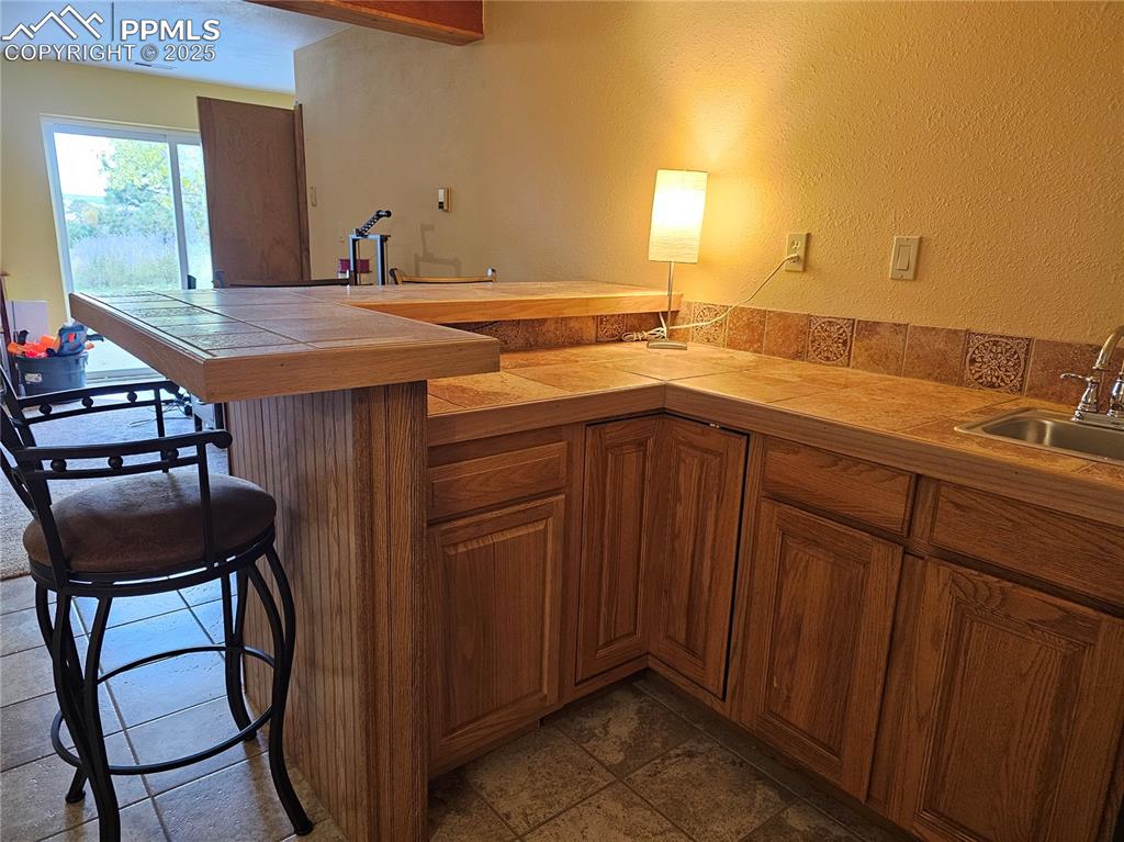 Image 19 of 44: Basement Rec Room Dry Bar with tile counters.