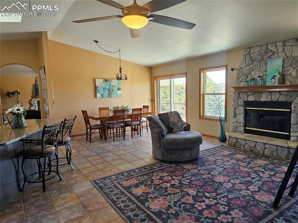 Image 4 of 44: Dinning room featuring lofted ceiling, and a stone fireplace