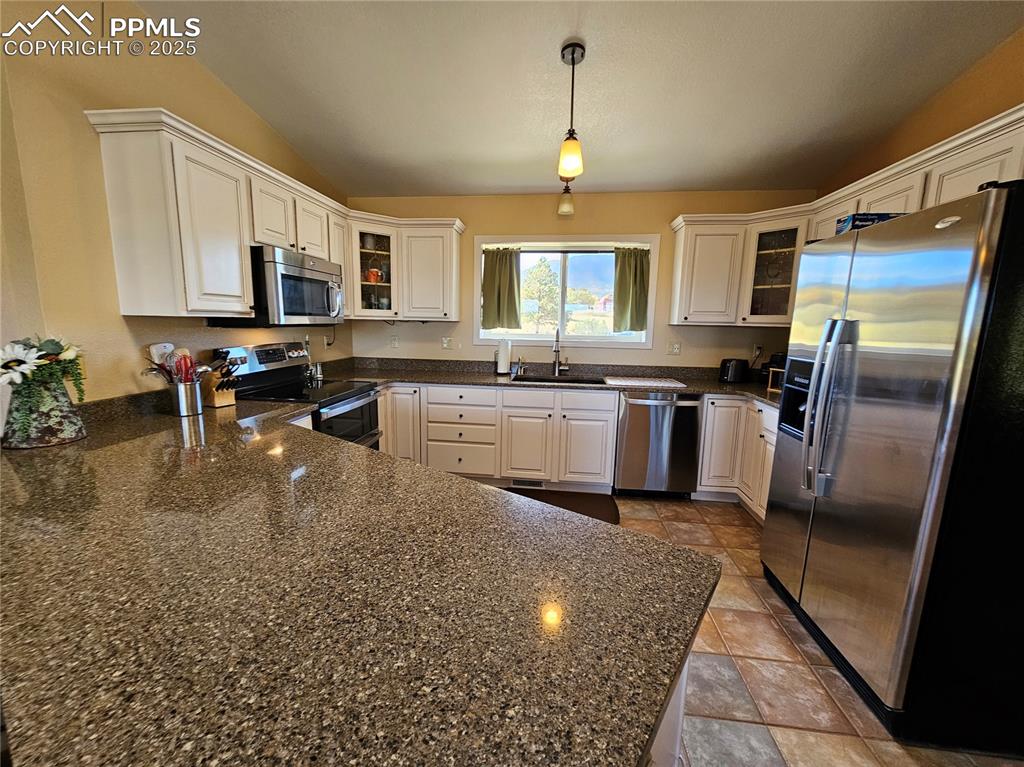 Image 9 of 44: Kitchen with appliances with stainless steel finishes, glass insert cabinet