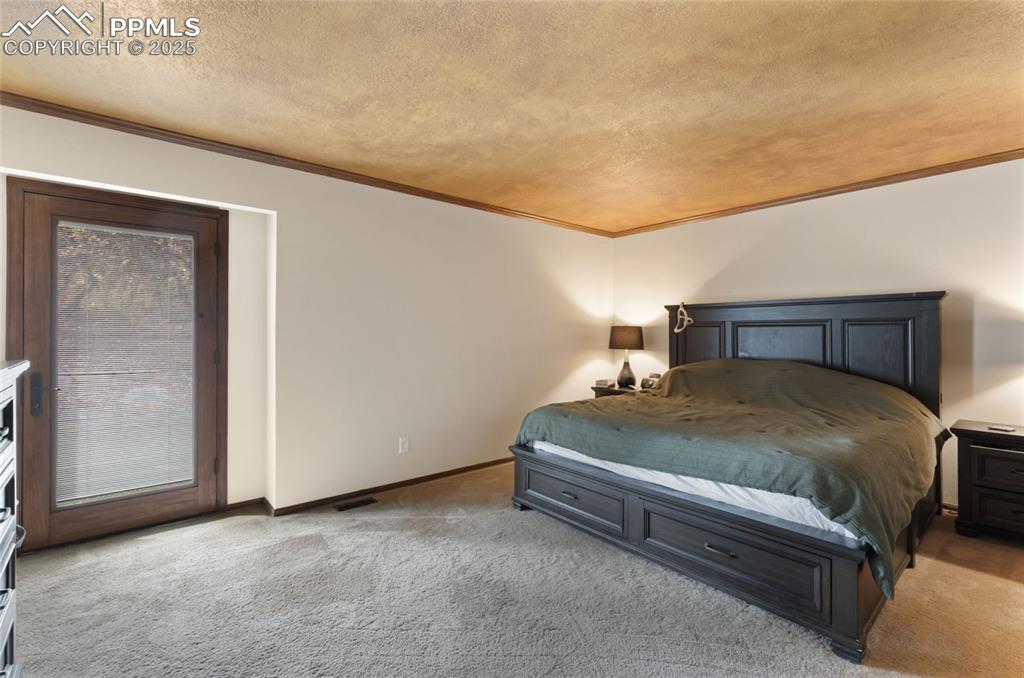 Image 12 of 21: Bedroom with light colored carpet, ornamental molding, and a textured ceili