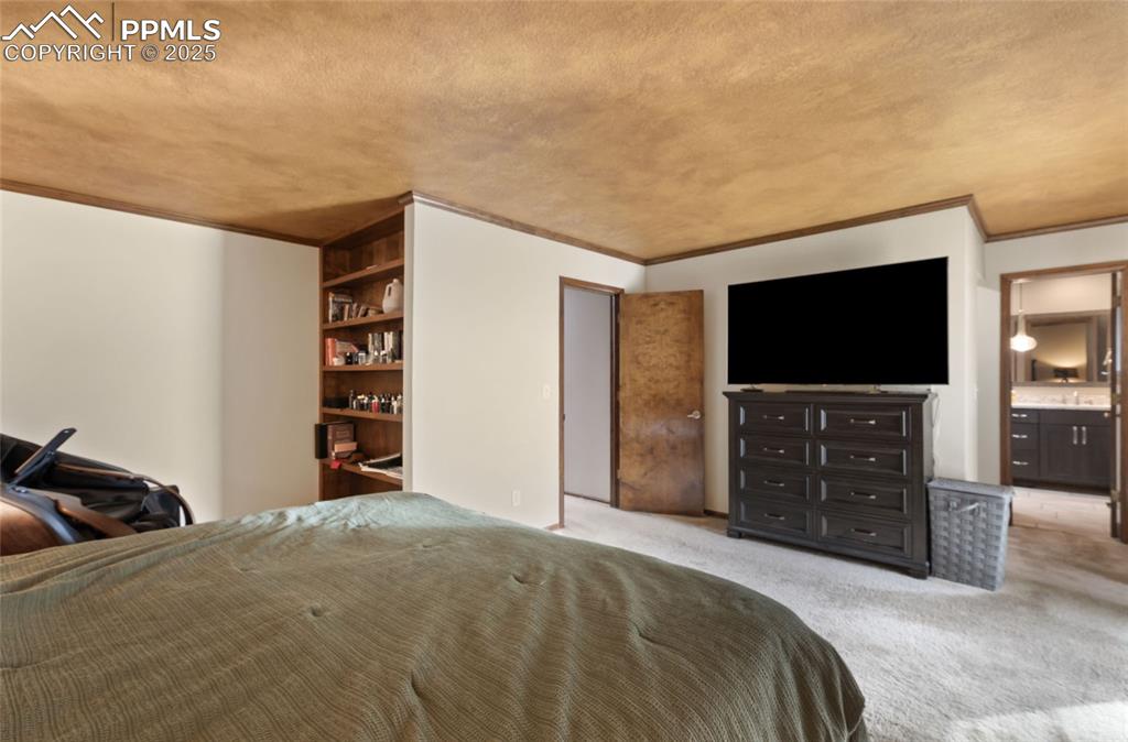 Image 13 of 21: Bedroom with ornamental molding, light carpet, and a textured ceiling