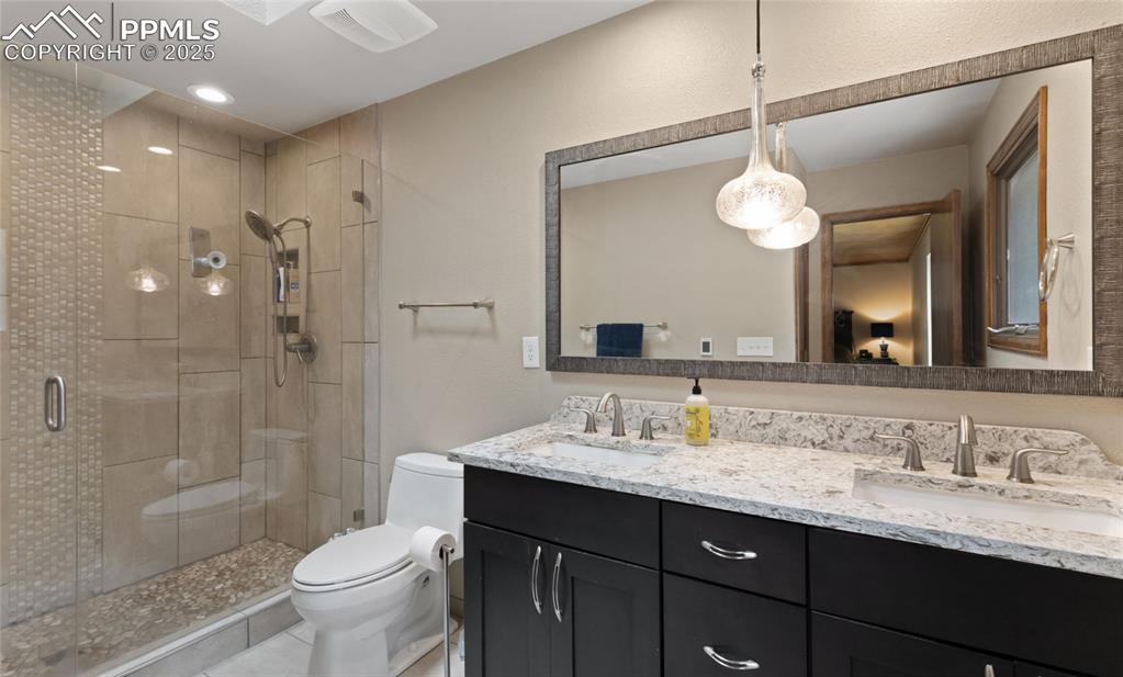 Image 16 of 21: Bathroom featuring double vanity, a shower stall, tile patterned floors, re